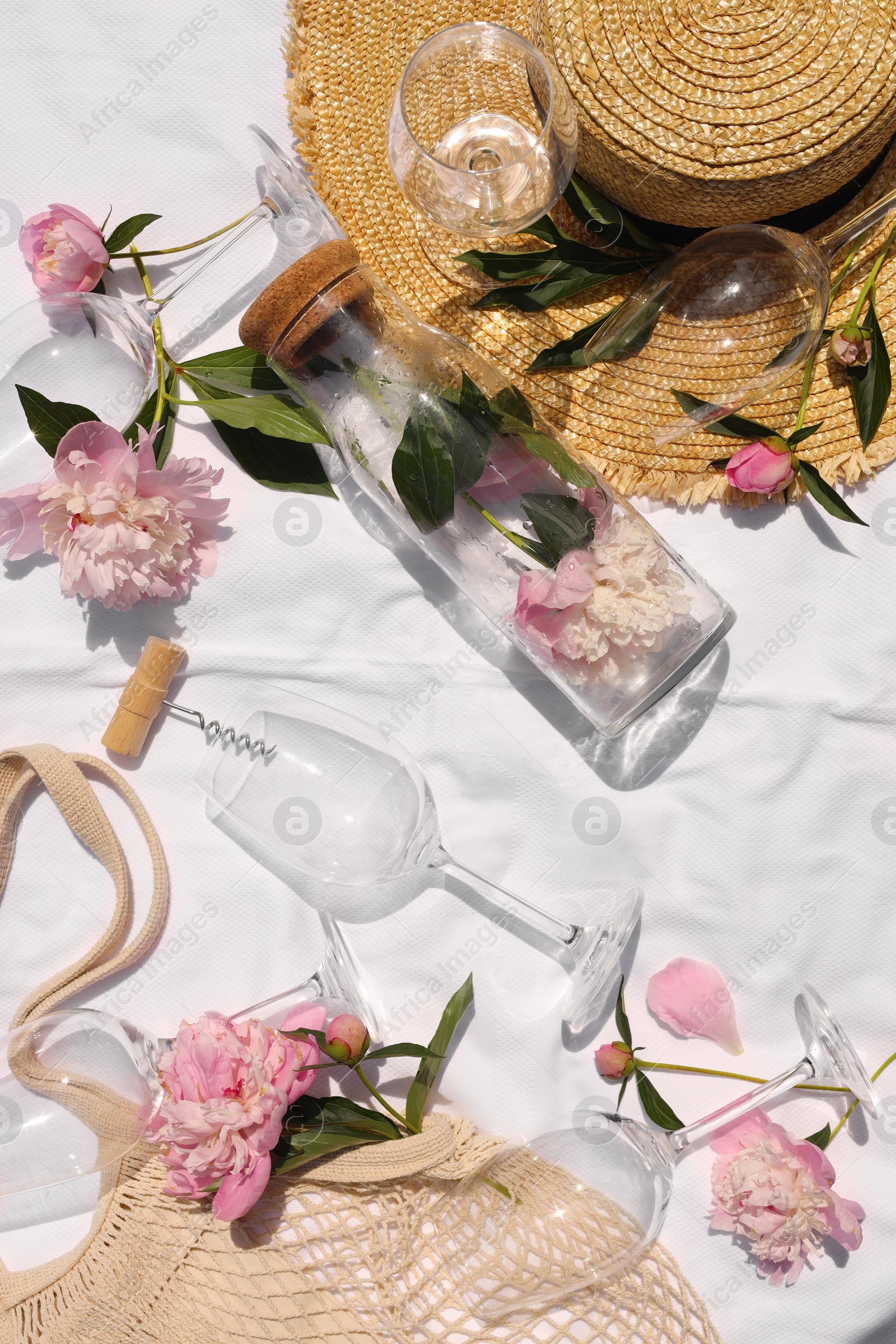 Photo of Flat lay composition with beautiful peonies and wineglasses on white fabric