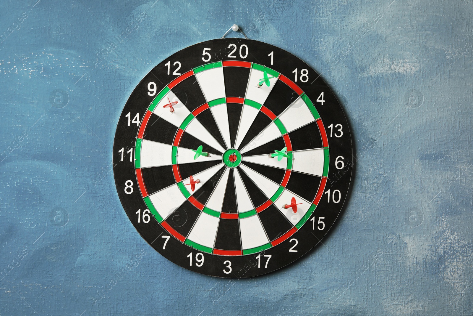 Photo of Arrows hitting dart board on blue wall