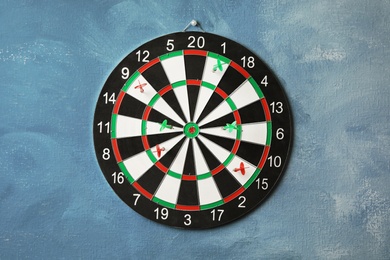 Photo of Arrows hitting dart board on blue wall