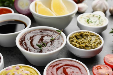 Different tasty sauces in bowls on grey table, closeup