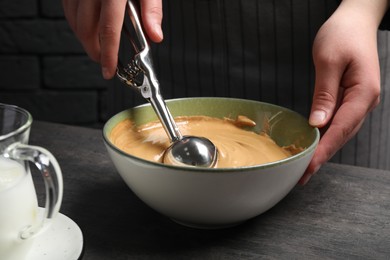 Photo of Woman taking cream from bowl at table, closeup. Making dalgona coffee