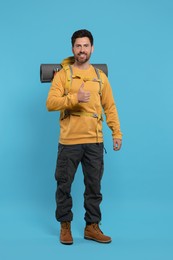 Photo of Happy man with backpack on light blue background. Active tourism