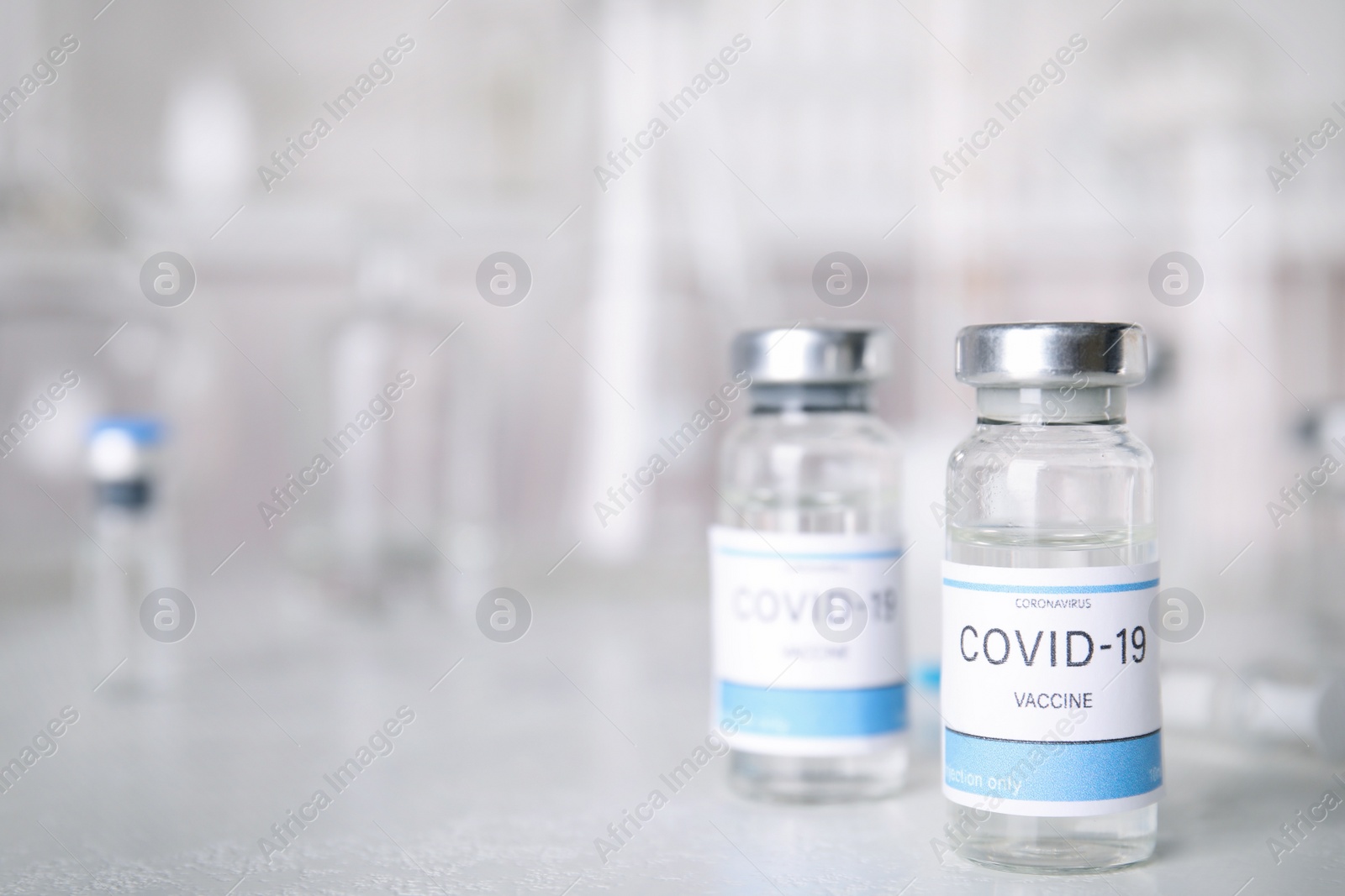 Photo of Vials with coronavirus vaccine on light table. Space for text