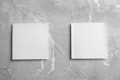 Photo of Blank note papers on light grey marble background, flat lay. Mock up for design