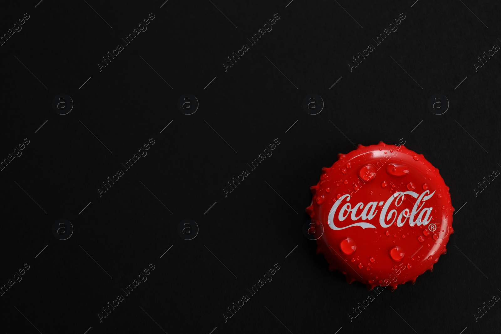 Photo of MYKOLAIV, UKRAINE - NOVEMBER 15, 2018: Coca Cola lid on black background, top view. Space for text