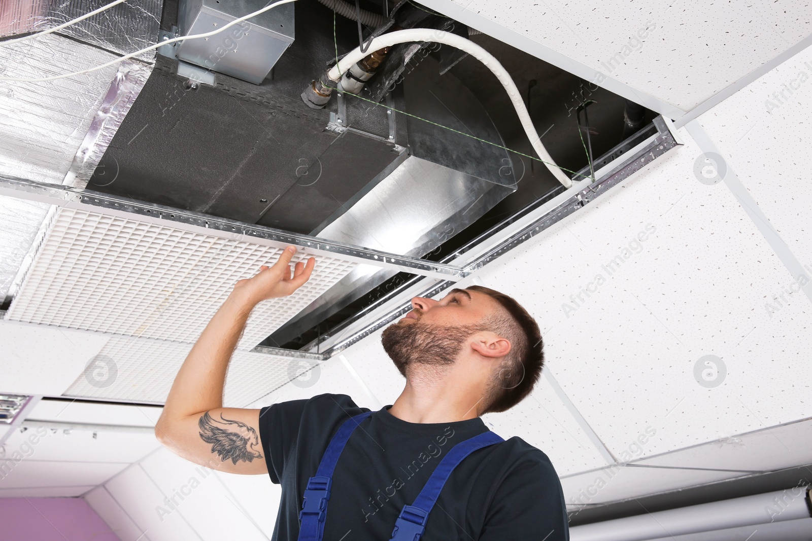 Photo of Young male technician checking air conditioner indoors