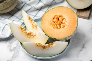 Photo of Tasty colorful ripe melons on white marble table