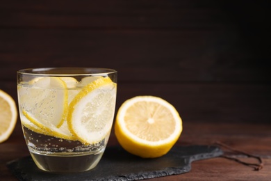 Soda water with lemon slices on wooden table. Space for text