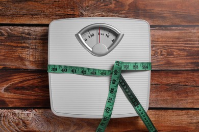 Scales and measuring tape on wooden background, top view. Weight loss concept