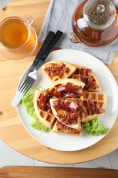 Photo of Tasty Belgian waffles served with bacon, lettuce and tea on wooden table, flat lay