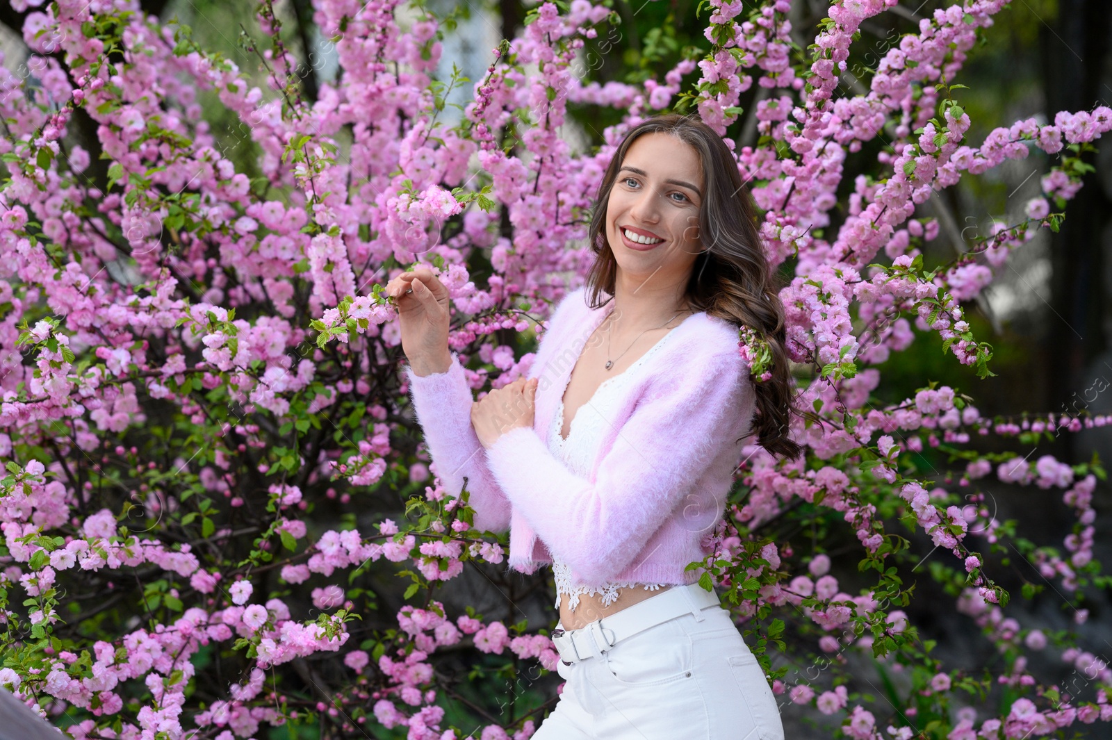 Photo of Beautiful young woman near blossoming sakura tree on spring day