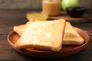 Photo of Crispy toasts on wooden table, closeup. Delicious breakfast