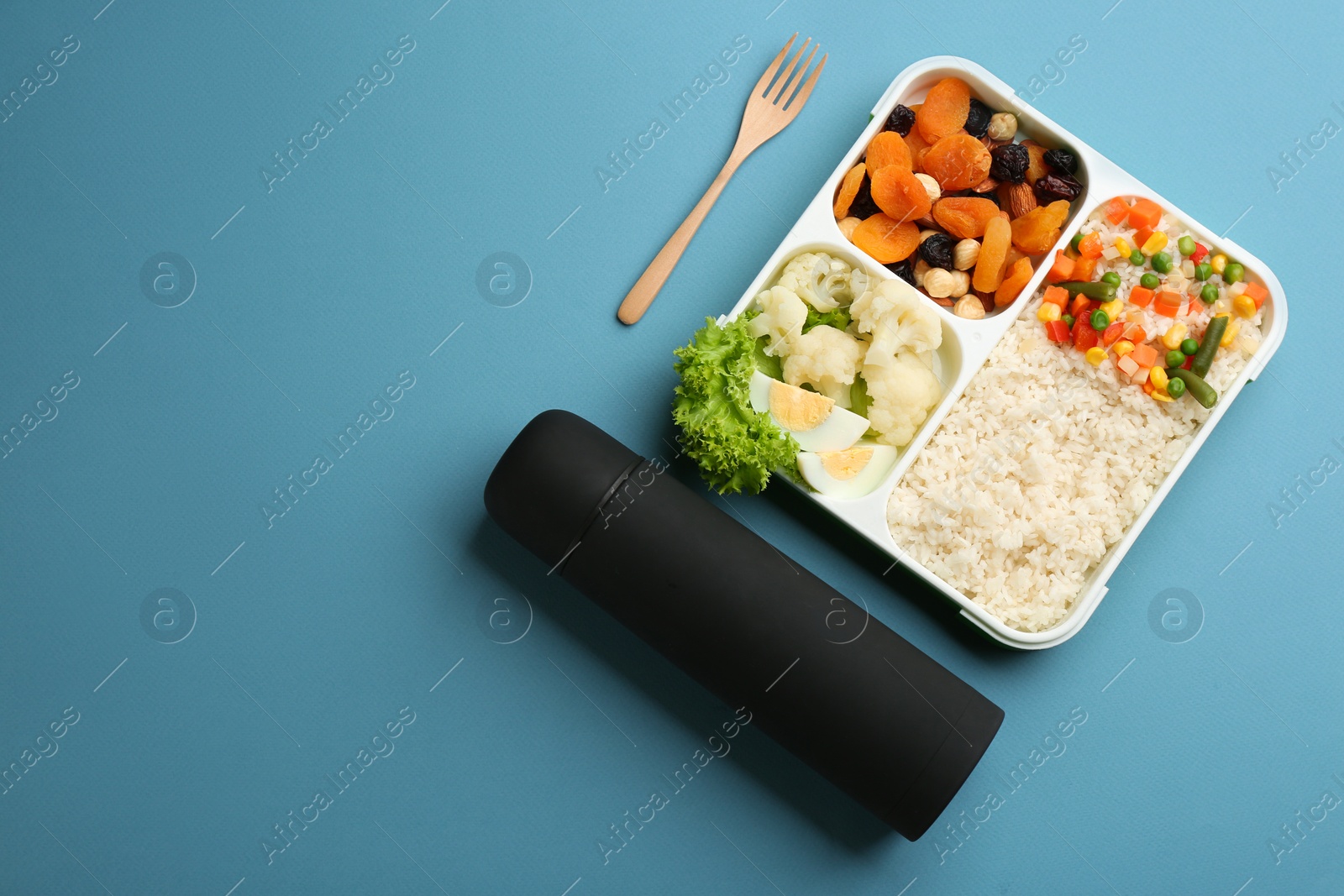 Photo of Thermos and lunch box with food on light blue background, flat lay. Space for text