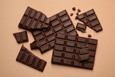 Photo of Pieces of delicious dark chocolate bars on beige background, flat lay