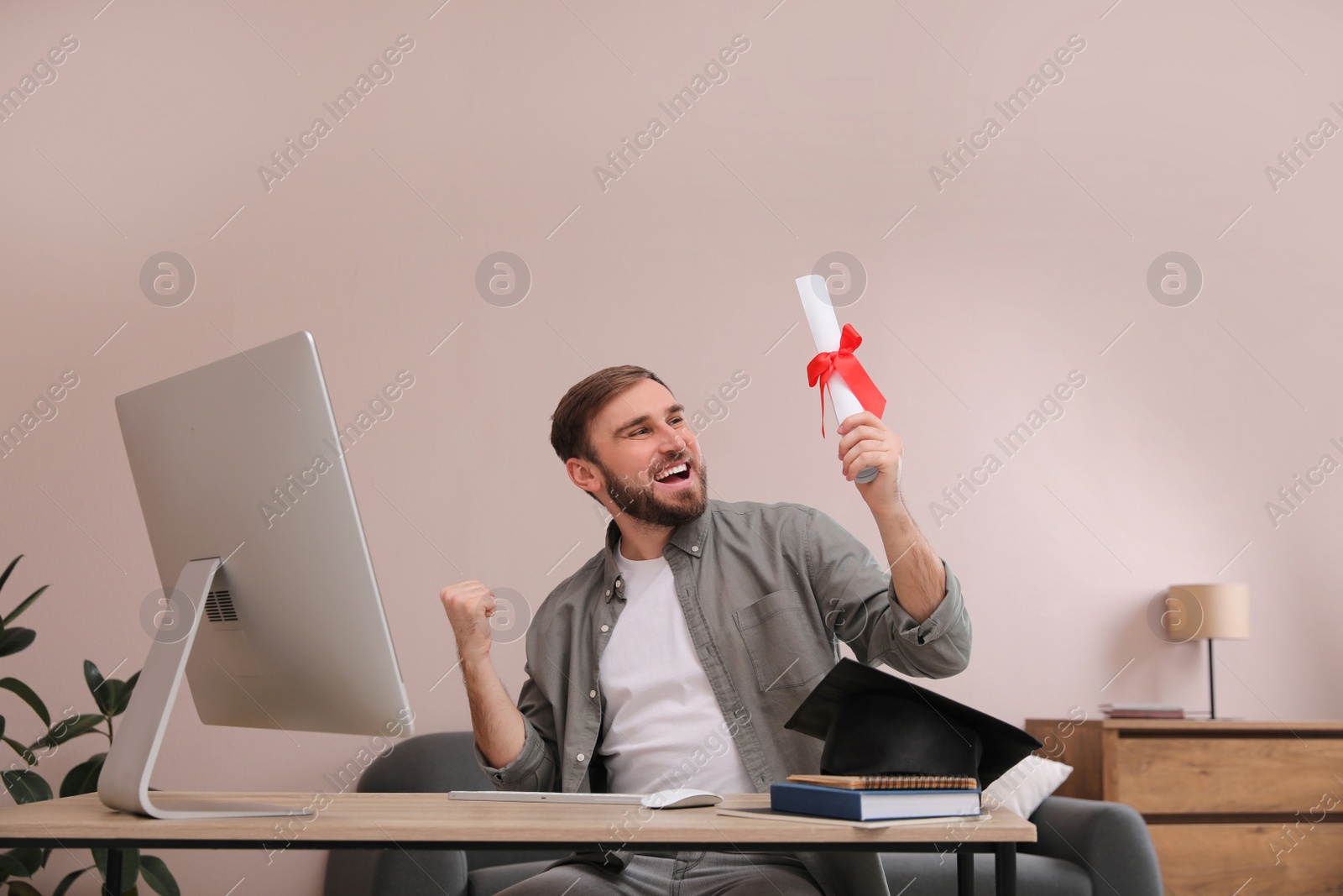 Photo of Happy student with graduation hat and diploma at workplace in office