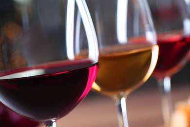 Glasses with different wines on blurred background, closeup