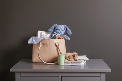 Photo of Mother's bag with baby's stuff on commode near gray wall