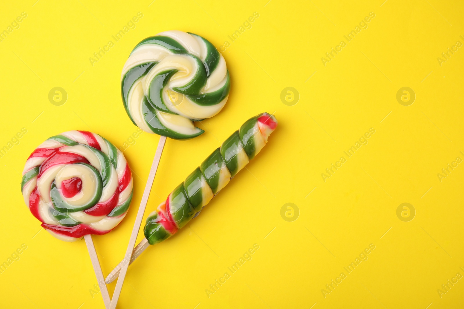 Photo of Colorful lollipops on yellow background, flat lay. Space for text