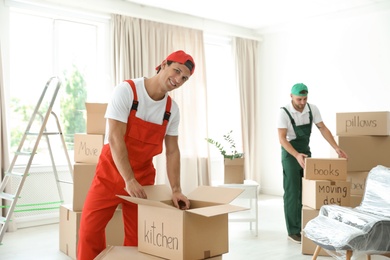 Male movers with boxes in new house