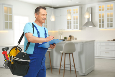 Image of Mature plumber with clipboard and tool bag in kitchen, space for text