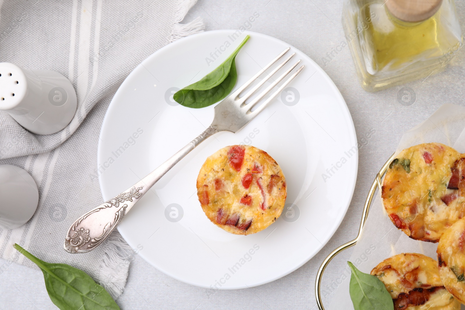 Photo of Freshly baked bacon and egg muffins with cheese served on light gray table, flat lay