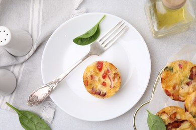 Freshly baked bacon and egg muffins with cheese served on light gray table, flat lay