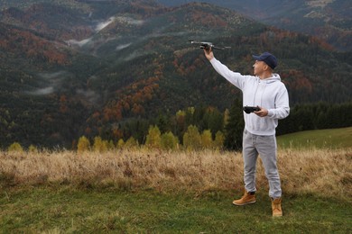 Photo of Young man with modern drone in mountains, space for text