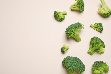 Photo of Fresh tasty broccoli on light beige background, flat lay. Space for text