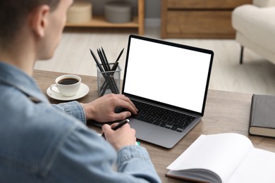 Photo of E-learning. Man using laptop during online lesson at table indoors, closeup