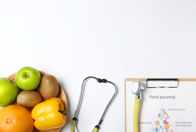 Photo of Fruits, vegetables, stethoscope and list of products on white background, top view. Visiting nutritionist