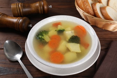 Photo of Tasty chicken soup with vegetables in bowl served on wooden table, above view