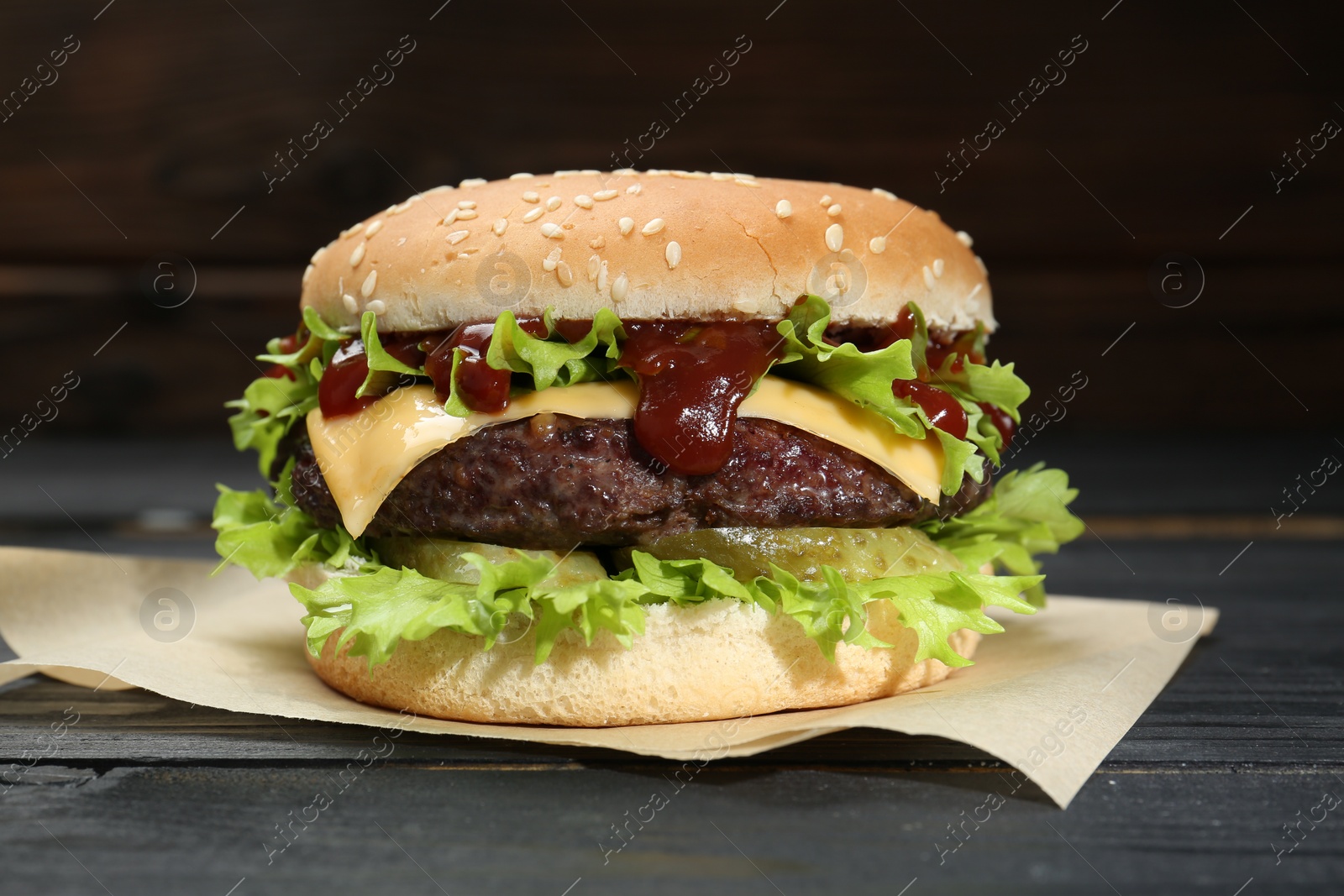 Photo of Burger with delicious patty on black wooden table