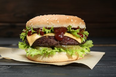 Photo of Burger with delicious patty on black wooden table
