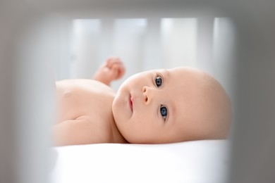 Cute little baby lying in crib at home