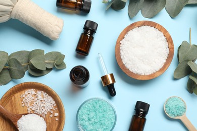 Photo of Different aromatherapy products and eucalyptus leaves on light blue background, flat lay