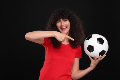Happy fan showing soccer ball on black background