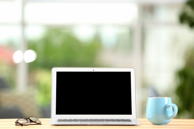 Laptop with blank screen on office table. Mock up for design