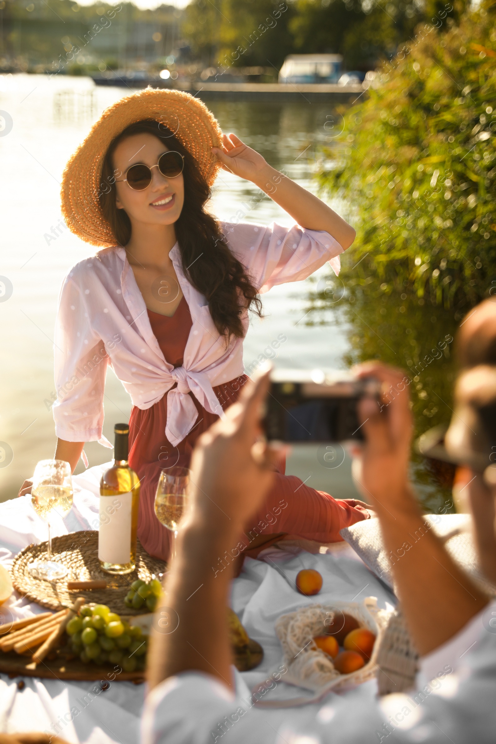 Photo of Man taking picture of girlfriend on pier at picnic, closeup