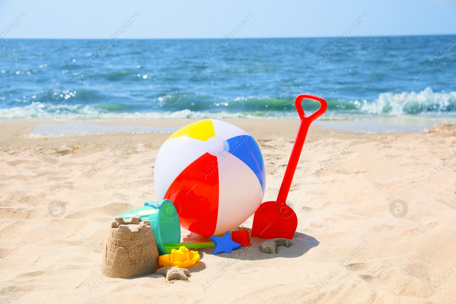 Photo of Different sand toys and beach ball near sea