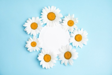 Beautiful floral composition with chamomile flowers and card on color background, top view