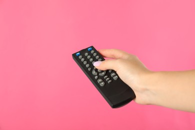 Photo of Woman holding remote control on pink background, closeup
