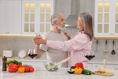 Photo of Happy affectionate senior couple dancing in kitchen