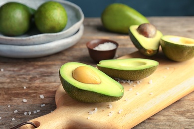 Wooden board with cut avocados on table