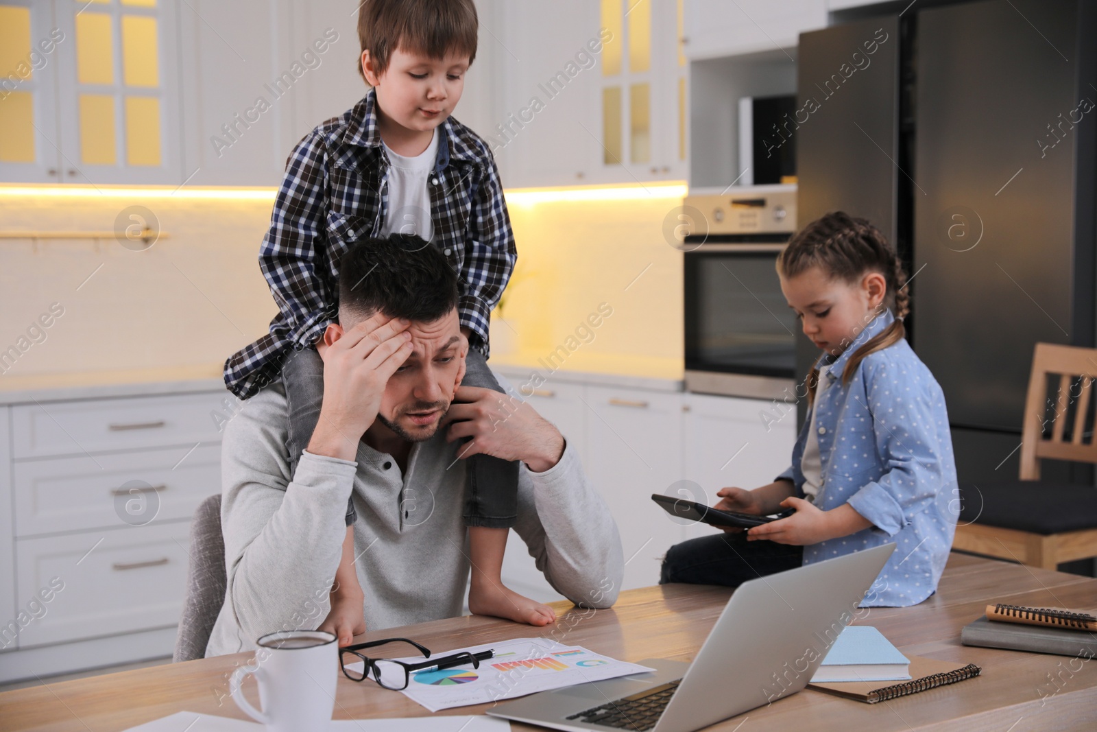 Photo of Overwhelmed man combining parenting and work at home