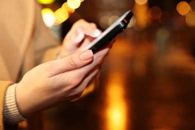Photo of Woman using smartphone on night city street, closeup. Space for text