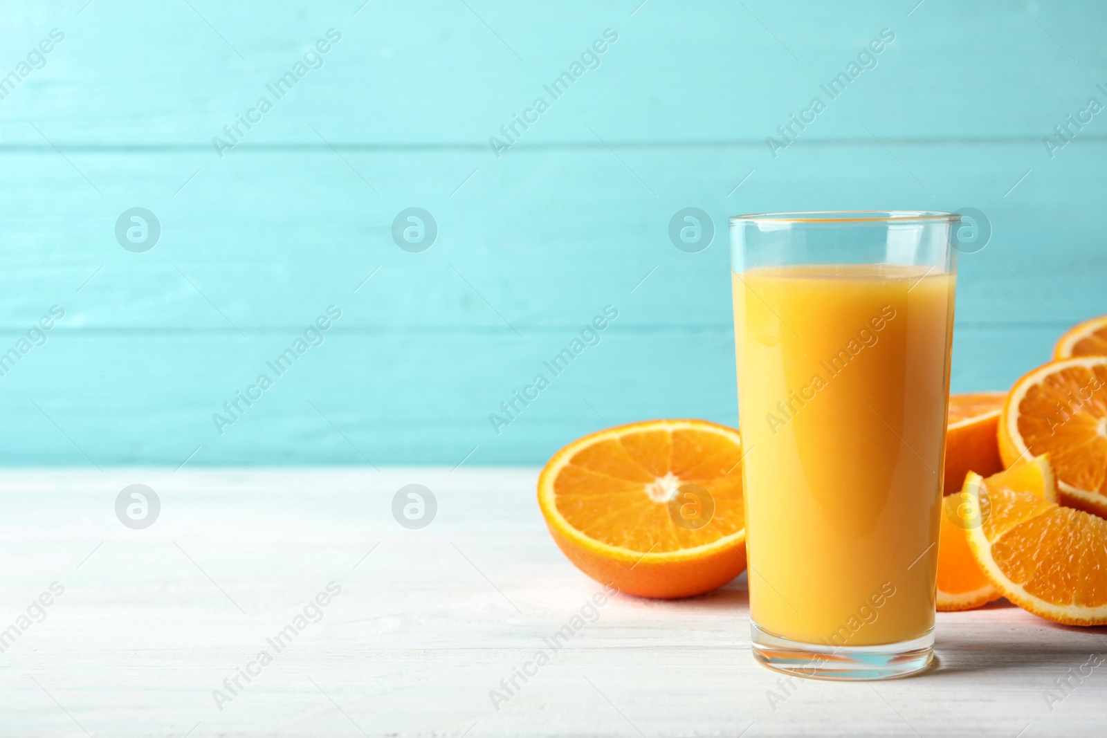 Photo of Glass of orange juice and fresh fruits on white wooden table. Space for text