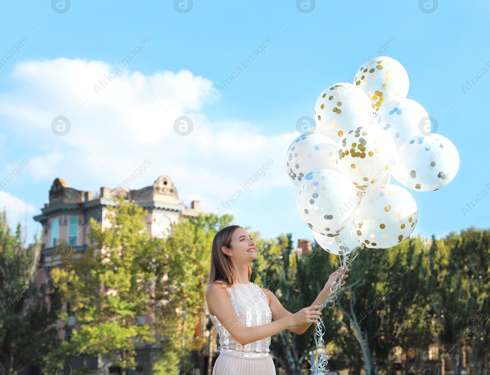 Photo of Beautiful teenage girl holding glitter balloons on street