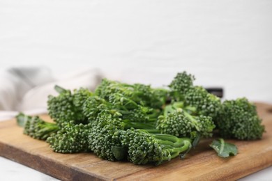 Fresh raw broccolini on wooden board, closeup. Healthy food