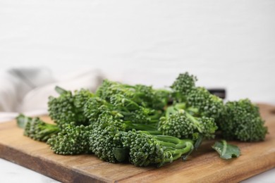 Photo of Fresh raw broccolini on wooden board, closeup. Healthy food