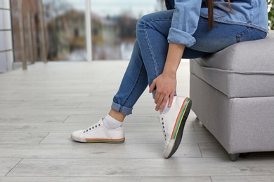 Young woman suffering from leg pain indoors, closeup with space for text